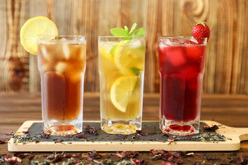 Three glasses of cold tea drinks including green tea with lemon and mint