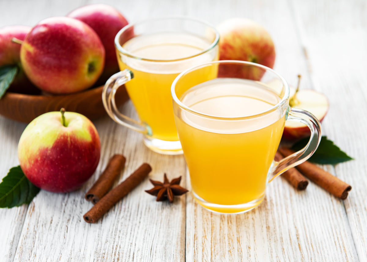 Apple cider with cinnamon sticks and fresh apples, warm spiced drink