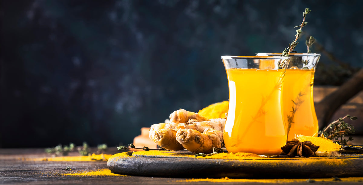 Glass of golden turmeric spice tea with fresh turmeric root and star anise